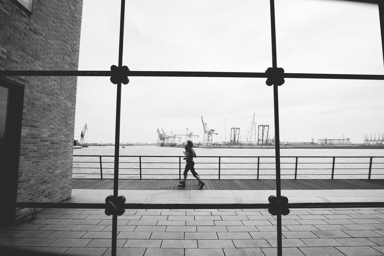 MAN WALKING ON ROAD AGAINST SKY