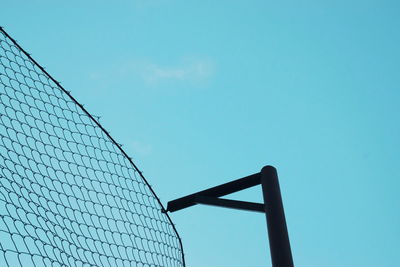 Low angle view of fence against blue sky