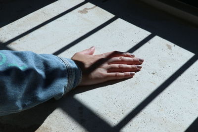 High angle view of hand on floor with shadow pattern 