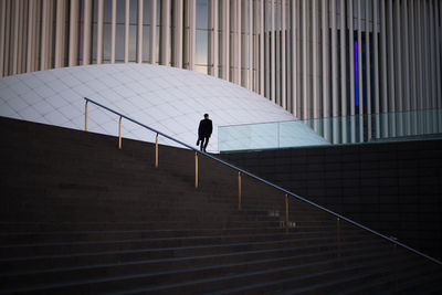 Rear view of silhouette person walking on staircase of building