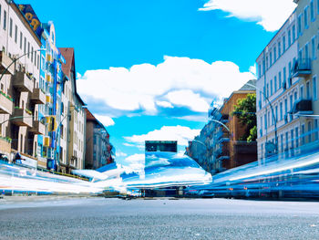 Road by buildings in city against sky