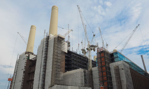 Low angle view of cranes against buildings