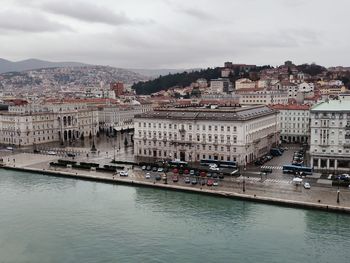 Buildings by river against sky