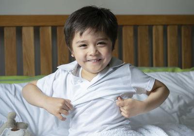 Portrait of smiling boy on bed at home