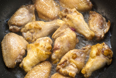 Cooking fried chicken wings in a pan