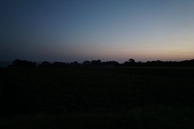 Scenic view of silhouette field against clear sky during sunset