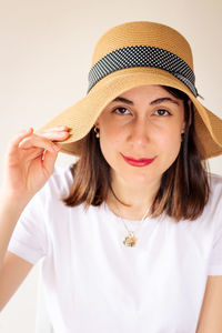 Portrait of young woman wearing hat against white background