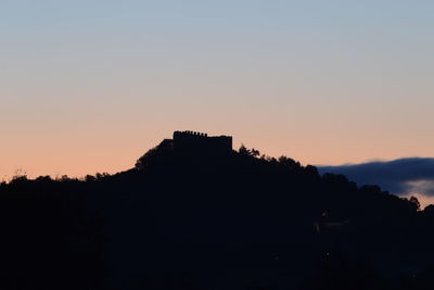 Silhouette built structure against sky at sunset