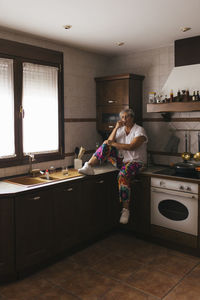 Woman smoking cigarette sitting on kitchen counter at home