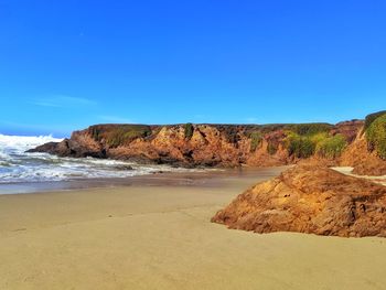 Rocks on beach against blue sky