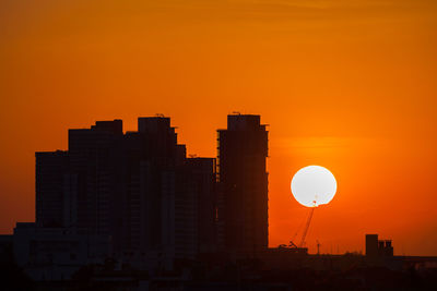 Silhouette buildings against orange sky