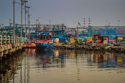 Fishing boats on pier against sky