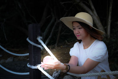 Midsection of woman holding hat while sitting outdoors