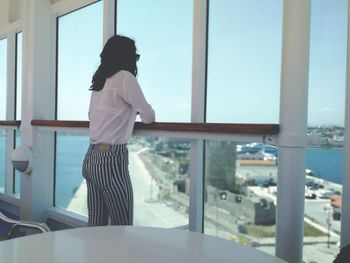 Rear view of woman looking through apartment window