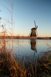 Traditional windmill on lake against sky