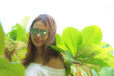 Portrait of young woman wearing sunglasses standing amidst plants
