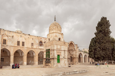 People outside historic building against sky