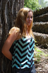 Young woman leaning on tree trunk