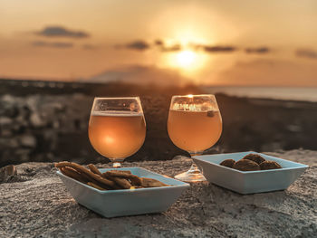 Close-up of drink on beach against sky during sunset