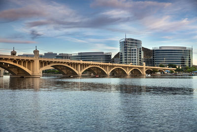 Arch bridge over river against sky in city