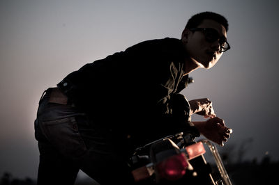 Man leaning on motorcycle against sky