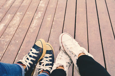Low section of friends wearing canvas shoes on boardwalk