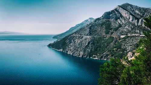 Scenic view of sea by rocky mountains against sky