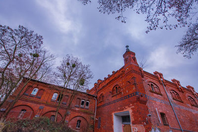 Low angle view of trees and building against sky