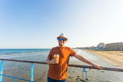 Portrait of young man standing in sea against clear sky