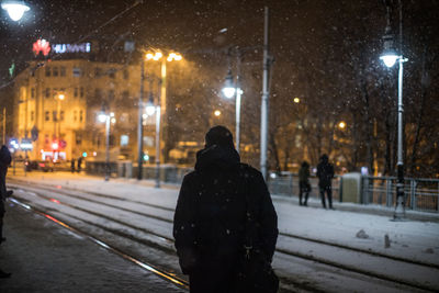 Rear view of people on snow covered street at night