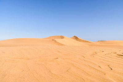 Scenic view of desert against clear blue sky