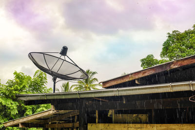 Low angle view of communications tower against cloudy sky