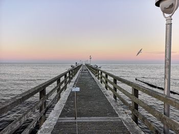 Pier over sea against sky during sunset