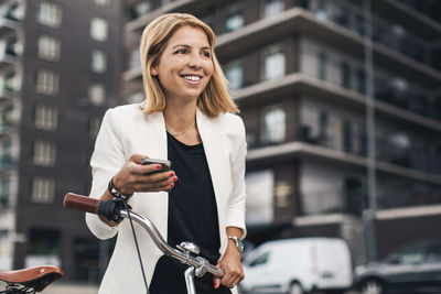 Smiling businesswoman using smart phone in city
