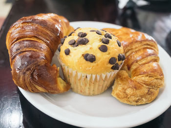 Close-up of muffin and croissants in plate on table