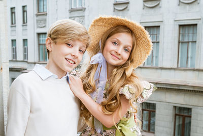 Beautiful boy and girl of school age posing for camera on urban background.
