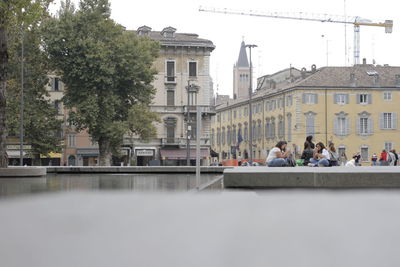 People at town square by buildings in city