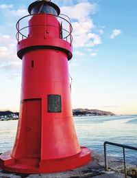 Lighthouse by sea against sky