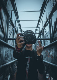 Portrait of man holding camera while standing on railing