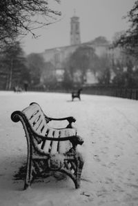 Empty bench in snow covered park during winter