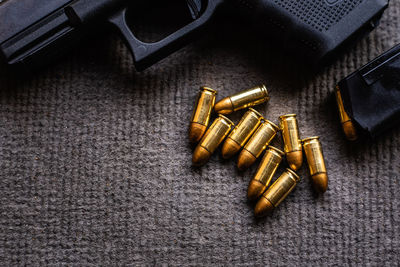High angle view of golden bullets and gun on textile