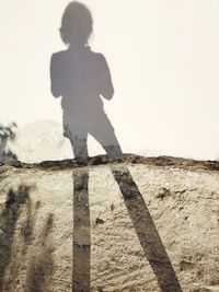 Shadow of man on wall against clear sky