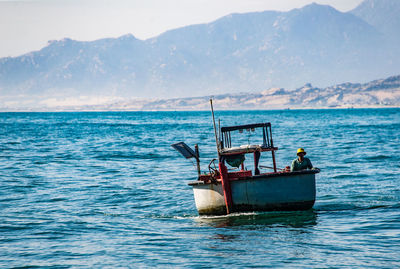 Fishing boat sailing in sea against sky