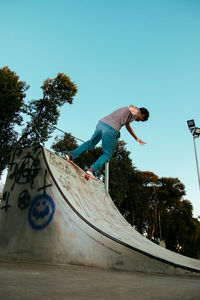 Low section of man skateboarding on skateboard against sky