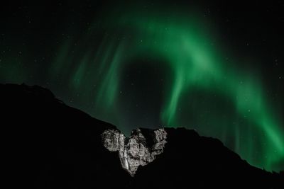 Low angle view of mountain against aurora polaris