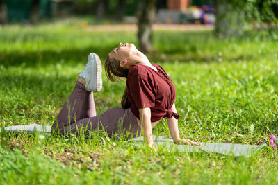 Side view of woman sitting on grassy field