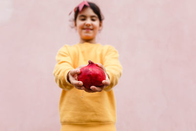 Hands of child holding bright red pomegranate