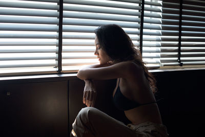 Young woman sitting on window at home