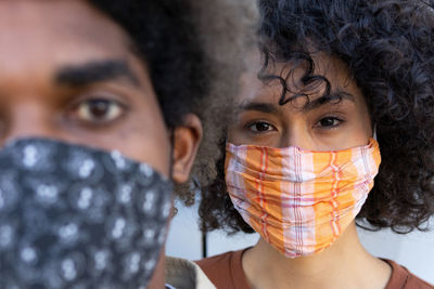 Crop unrecognizable ethnic young man and woman with afro hair in protective masks looking at camera