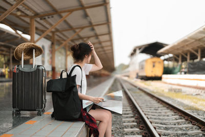 Side view of woman sitting on railroad station